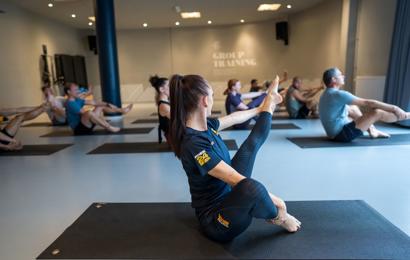 Pilates gruppträning på Fitness24Seven med instruktör i förgrunden med rakt ben 